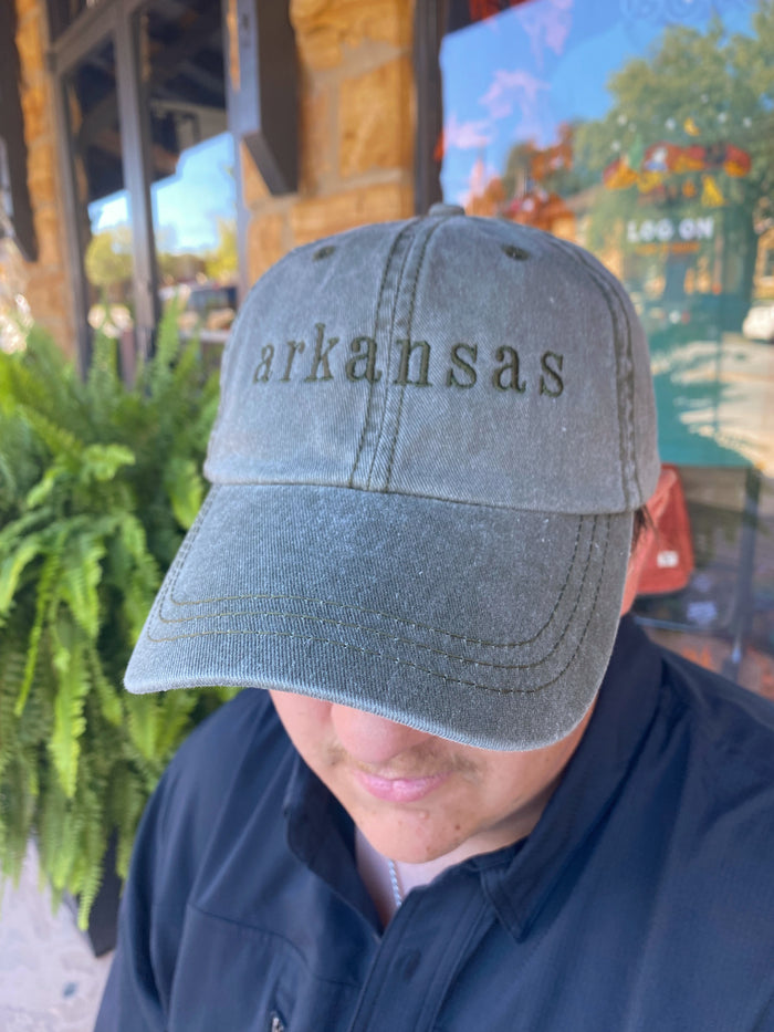 green embroidered Arkansas cap being worn outside in front of a green fern plant