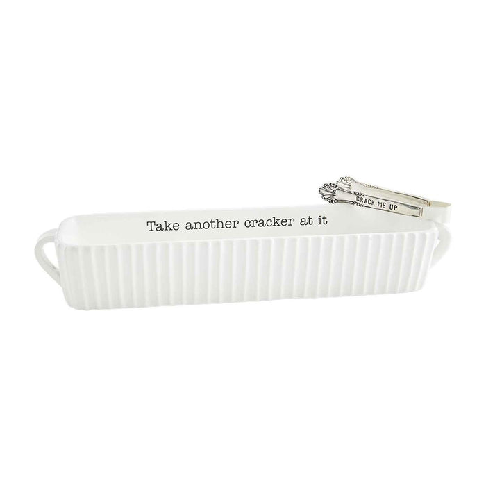White ceramic cracker dish with text and silver tongs on a white background
