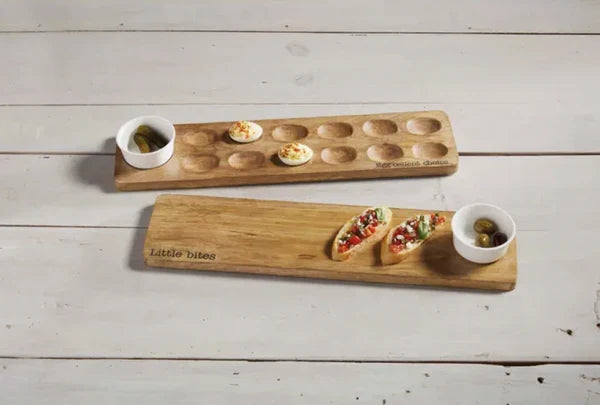 Two wooden appetizer platters with food on a light wooden surface