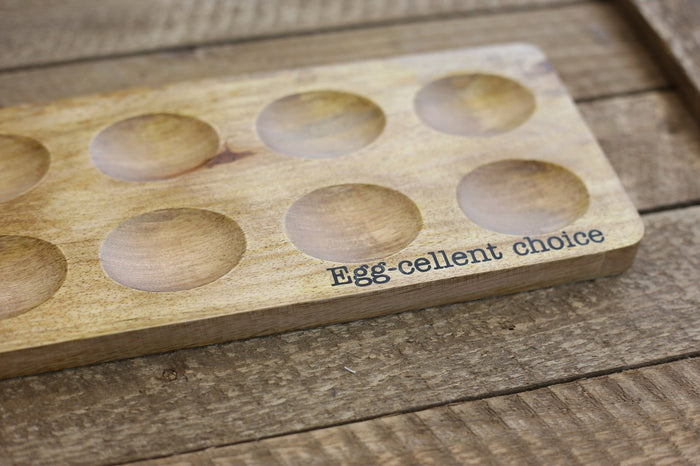 Wooden egg holder with circular slots on a wooden surface, featuring the text 'Egg-cellent choice'.
