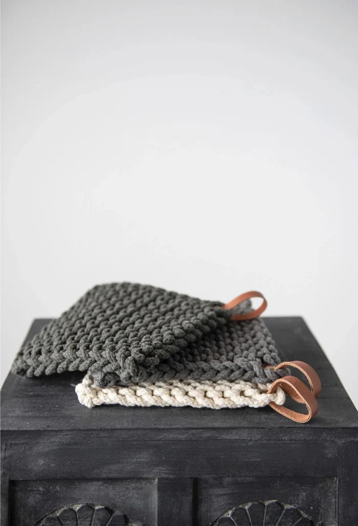 hand crocheted cotton pot holder on a black table with a cream background