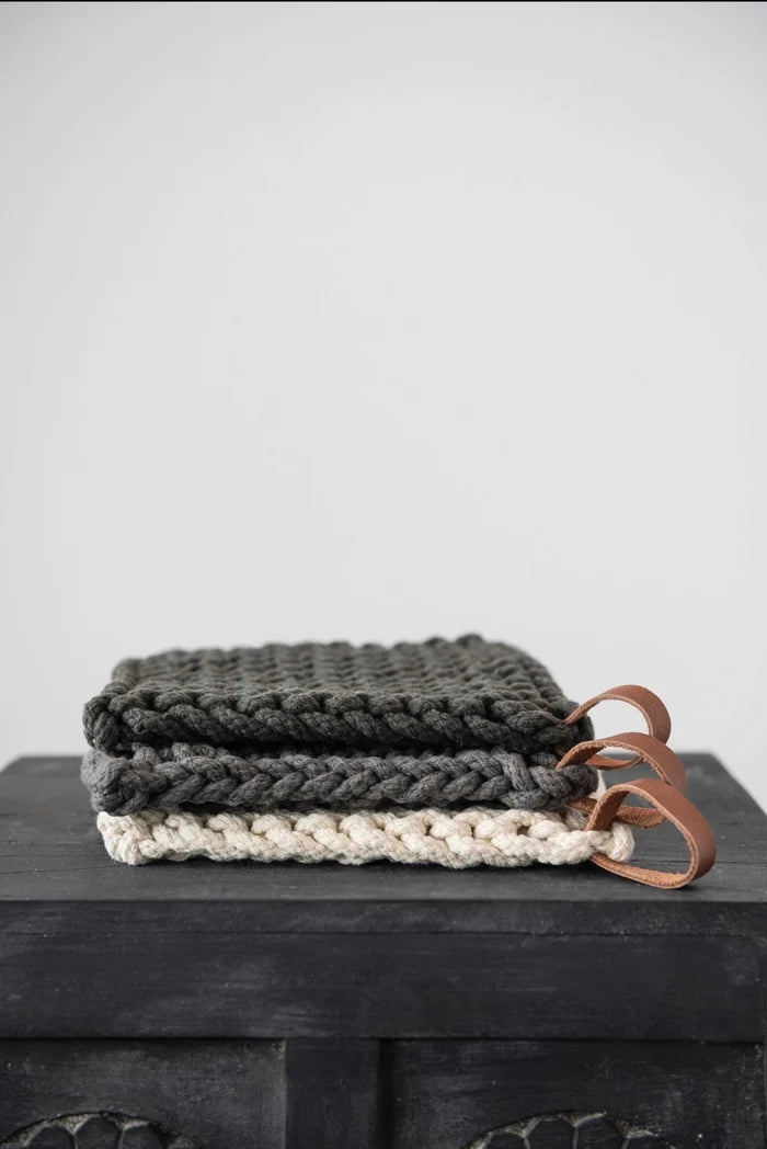 hand crocheted cotton pot holder on a black table with a cream background
