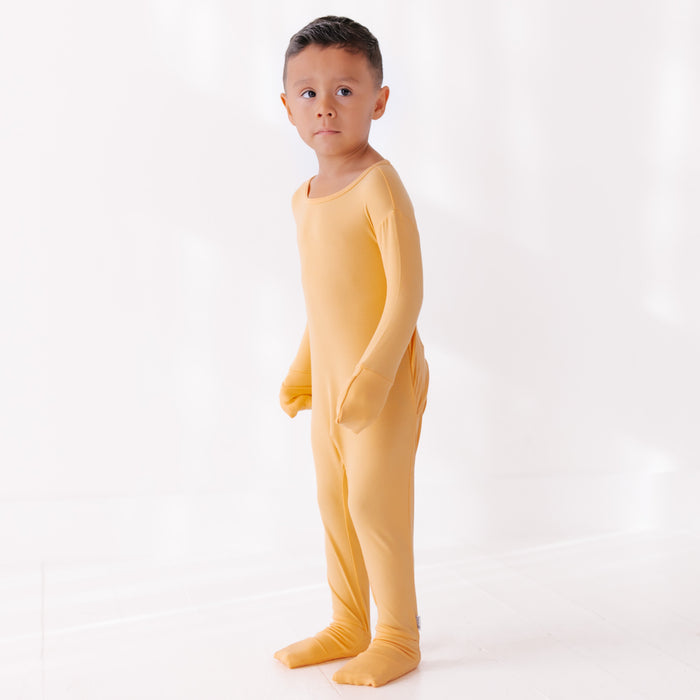 Child wearing a yellow onesie on a white background