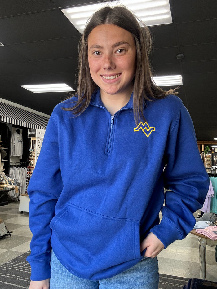 Person wearing a blue hoodie with a yellow logo indoors