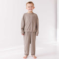Child wearing a beige pajama set on a white background